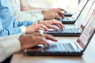 Multiple workers sitting together typing on laptops, Experience Management  | DXC Technology